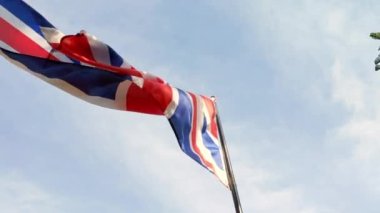 Low angle and cinematic shot of the British flag fluttering in the wind. Patriotism and nationalism concept