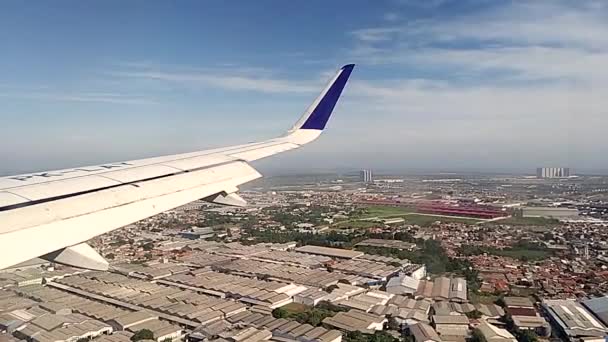 慢动作一架商用飞机的机翼在晨云从飞机窗向西雅加达工业区上空飞去 2023年2月16日坐飞机旅行 — 图库视频影像