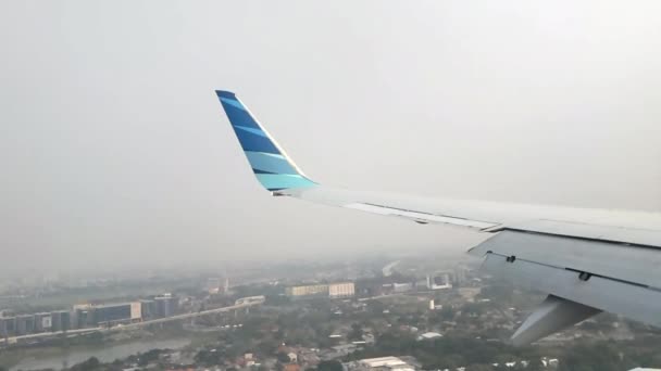 スローモーション 商用航空機の翼は着陸前に霧の多い都市部を飛行した 飛行機の窓からの眺め 空気で旅する — ストック動画