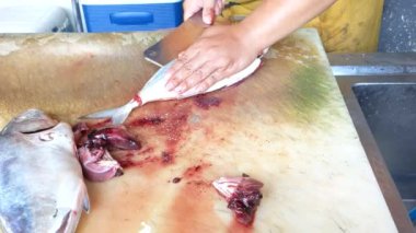 Sinematik çekim. Restorandaki ızgara deniz ürünleri menüsünü hazırlama süreci. Asyalı genç adamın eli ızgaradan önce keskin bir bıçakla balık keser. Deniz ürünleri konsepti hazırlanıyor