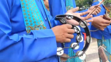 Sinematik çekim. Betawi kabilesinin müzikal performansında çift sıra tef çalan genç bir müzisyenin eli.