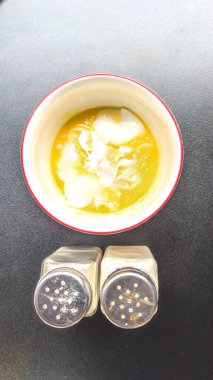 Kahvaltı menüsünün yüksek açılı görüntüsü yarı pişmiş yumurtalar, toz biber ve siyah tahta masadaki konteynırlar içindeki ince tuz ile tamamlanmış. Sağlıklı kentsel beslenme kavramı