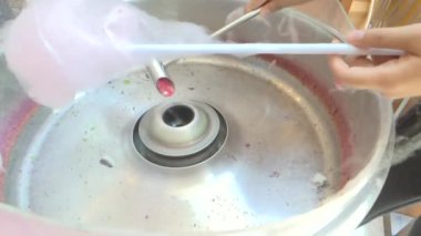 Genç kadınların ellerinin pamuk şekeri makineye attığı sinematik bir çekim. Her yaştan, eğlenceden ve eğlenceden oluşan sokak yemekleri konsepti.