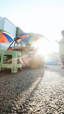 Tegal, Central Java, Endonezya. 5 Nisan 2015. Düşük açı. Şehir meydanında Kerak Telor olarak bilinen yumurta kabuğu yapan bir sokak satıcısı, otantik sokak yemeği kültürünü ön plana çıkaran, hevesle bekleyen bir kadınla birlikte..