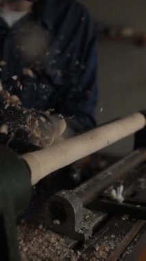 Eldivenli bir marangozun eli, işlenmiş bir odun parçasını bir aletle öğütür. Atölyedeki bir makinenin üretim süreci, yavaş çekim dikey olarak