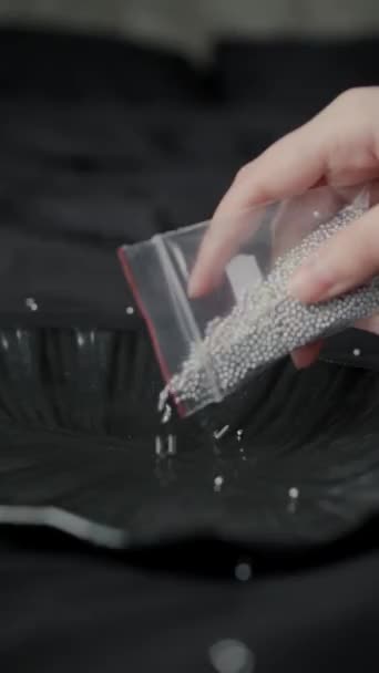 Female Beaders Hand Pours Silver Beads Plastic Bag Decorative Black — Stock Video