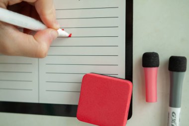 Öğrenciler hafta çizelgesini siyah-beyaz planörlü duvara kırmızı bir kalemle yazıyorlar. Ders listesi için yakın çekim yeri