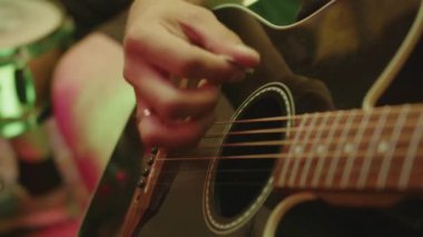 Müzisyenler parmaklarında bir sentezleyici tutuyor ve gitar tellerine vuruyorlar. Müzik enstrümanları çalmayı öğrenmek, yavaş çekimde bir rock grubunun performansı.