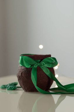 Yeşil saten yay ve parlak leprikon altın ışıklarıyla küçük kahverengi bir sürahi. DIY St. Patricks Günü dekorasyonu, beyaz arkaplanda el yapımı dikey olarak yakın plan