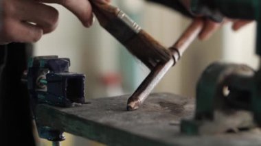 Sanatçının elleri, el yapımı ahşap bir değneği fırça kullanarak lekeli bir karanlık solüsyonla kaplıyor. Bir marangozluk atölyesinde çalışıyorum.
