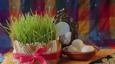 Bir el bir şamdanı tutar ve Nevruz bayramı için dekore edilmiş bir masaya koyar buğday tohumu, bir kase yumurta ve bir ayna yanında. Yeni yıl için İran halkının gelenekleri, yakın plan.