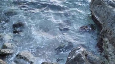 Suyun arka planı, deniz dalgaları, okyanus dokusu, yavaş çekim yakın çekim. Soğuk mevsimde kayalık arazisi olan deniz kıyısı