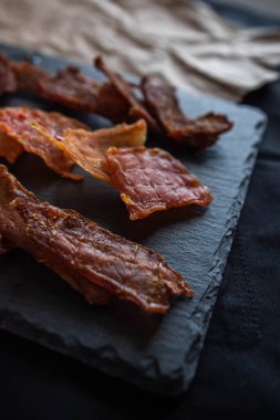 Kurutulmuş kurutulmuş kurutulmuş etin farklı türleri taş siyah bir kare tadımlık tabakta parçalar halinde serilmiştir. Atıştırmalıkların hazırlanması, bira için atıştırmalıklar, dikey olarak