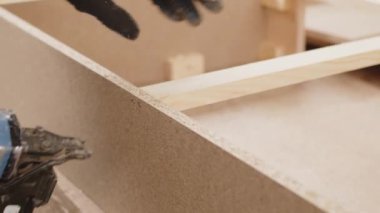 Bir işçi eli, ağır çekimin yakın çekimini bir parça talaş zımbasıyla birbirine bağlar. Mobilya üretme süreci