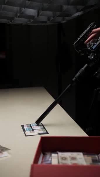 ビデオグラファーの腕は ライトテーブルに横たわるスタンプのコレクションを目的としたマクロレンズの焦点を調整します 撮影とビデオ作成のプロセス 垂直にクローズアップ — ストック動画