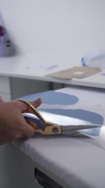 Kesiciler gelecekteki ürünün detaylarını terzi makası ile yavaş çekimde kesiyor. Giysi Hazırlama Süreci, Yakın çekim, Dikey Çekim