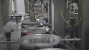 Üretim hattındaki otomatik mekanizma teneke kutuları birer birer boyayla dolduruyor. Taşıma anı, fabrikada optimizasyon işlemi, yakın çekim.