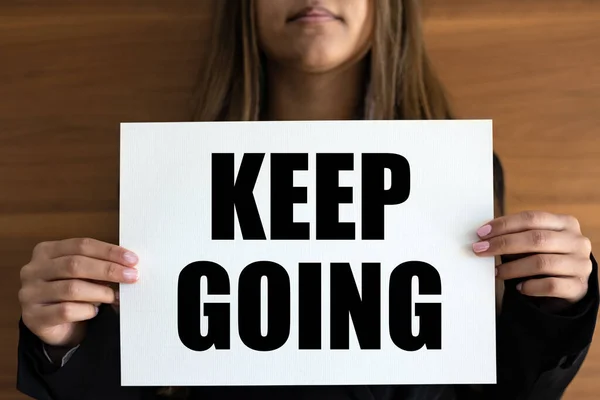 Keep going. Woman holds a white page with text \