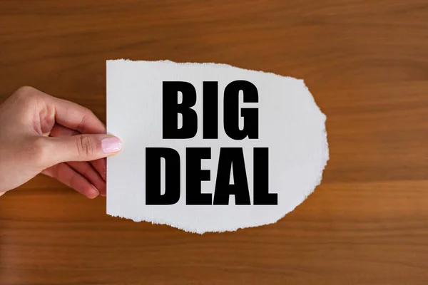 Big deal - close up text on the slip.  Woman hand holds a piece of paper with text. Business, sale, discount, commercial activity, buying and marketing.