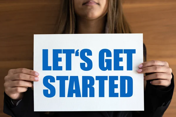 Let\'s get started. Woman holds a white page with blue text. New beginning, business, inspiration, motivation, encouragement and message.