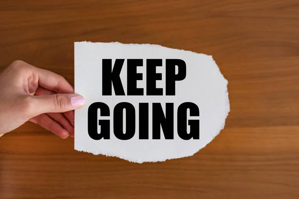 Keep going. Woman hand holds a piece of paper with a note, keep going. The way forward, continuity, motivation, positive emotion, inspiration and encouragement.