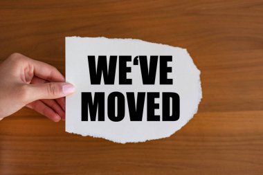 Taşındık. Makbuzun üzerindeki metni kapat. Kadın eli yazılı bir kağıt parçası tutuyor. Bilgi işareti, yeni iş yeri, konum, taşınma ve yeni adres.