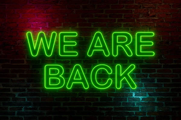 We are back, neon sign. Brick wall at night with the text \
