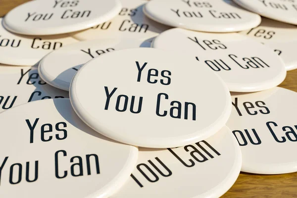 Yes You Can badge. White badges laying on the table with the message \
