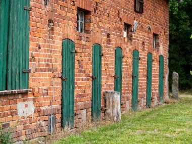 Eski hayvan kulübesi. Çiftlikte eski yeşil ahşap kapıları olan eski tuğla kulübe..