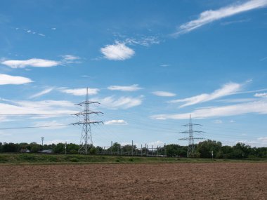 Pürüzlü ve çok kuru tarım arazisi. Arka planda elektrik direkleri olan tarım sahnesi. Az bulutlu mavi gökyüzü. 