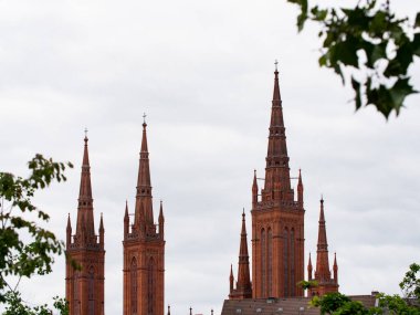 Üstünde haç olan kilise kulesi. Kırmızı tuğlalı kilise kulelerini kapatın. Almanya 'da Hessen, Wiesbaden' in merkezindeki antik ve tarihi bina. Çok bulutlu bir gün..