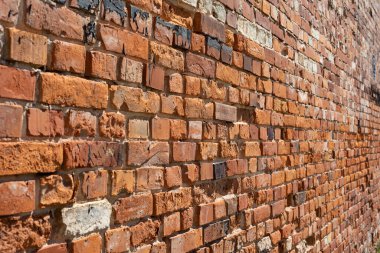 Eski bir bitkinin tuğla duvarı. Eski bir fabrikanın yıpranmış kırmızı tuğla duvarı. Yüzey kısmen çatlamış.. 