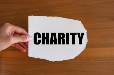 Hayırseverlik. Kadın eli, üzerinde bir not olan bir kağıt parçası tutuyor. Destek, yardım eli, bakım, sosyal meseleler, birlikte, meşgul, fayda ve insanlık.