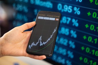 Mobil ekranda yükselen borsa endeksi. Kadının eli cep telefonunu tutuyor. Ekranda yükselen güçlü çizelge. Borsa, finans rakamları, ticaret ve iş konsepti. 