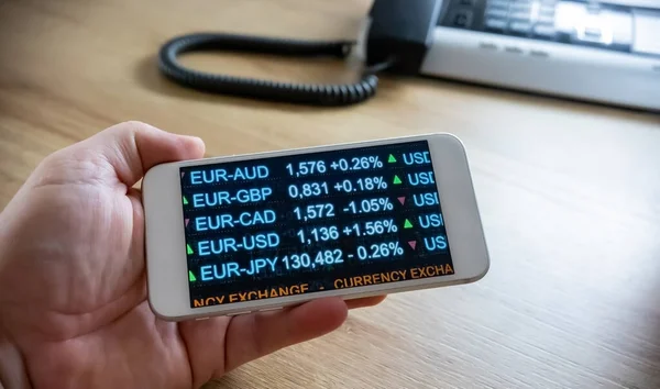 US dollar currency exchange rates. Hand holds a mobile phone with information about USD exchange rates. Currency trading and financial data.