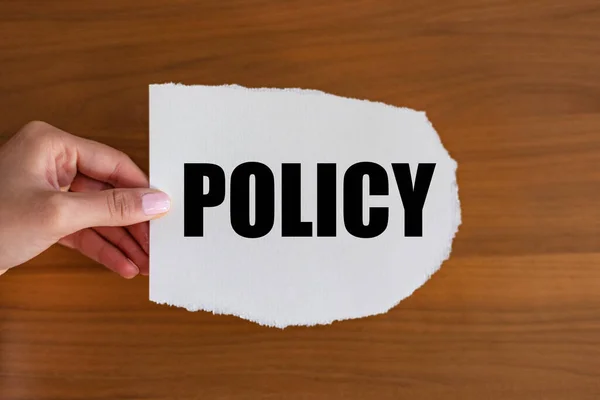Policy. Woman hand holds a piece of paper with a note. Condition, guide, rule, regulation, legal, strategy, prevention, method, definite course, decisions and procedure.