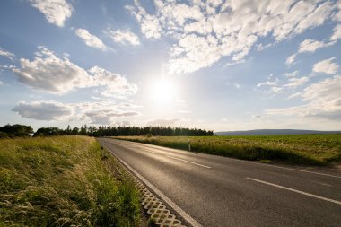 Rodheim, Wetterau, Hesse, Almanya, Haziran 2020: Yol ve tarla manzarası, mavi gökyüzü ve bazı bulutlar. Arka planda Forrest.