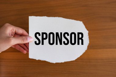 Sponsor. Kadın eli, üzerinde bir not olan bir kağıt parçası tutuyor. Yardım, bağış, destekçi, patron, kefil, kefil, kefil ve sorumluluk.