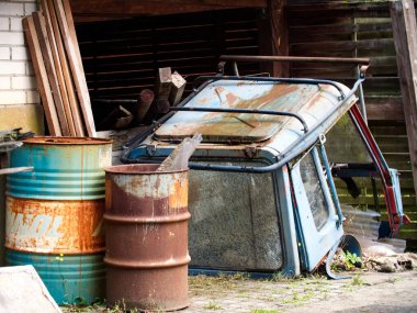 Paslı hurda. Eski hurda bir varil ve eski mavi bir sürücü taksisi.