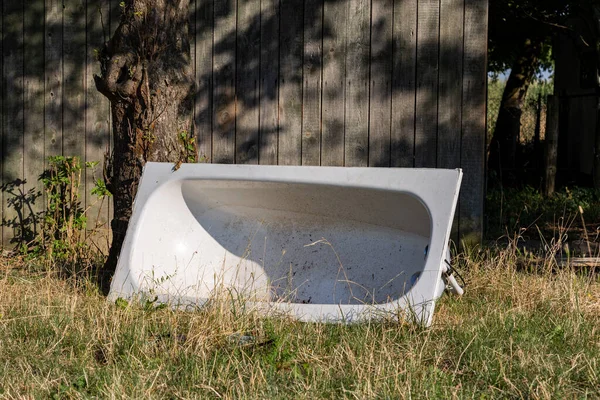 stock image White dirty bathtub. Bathtub lies on the lawn in front of a shed.