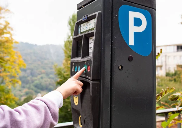 Woman pushes the button from a parking ticket machine to get her parking ticket. Transport, parking place in Germany.