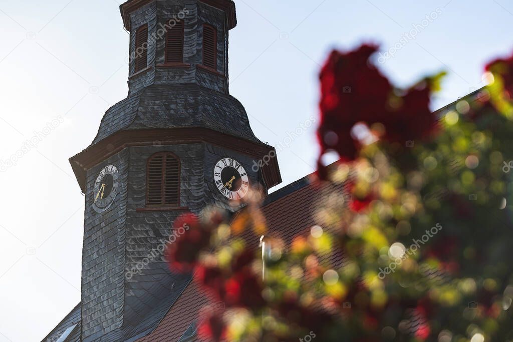 Reloj de iglesia rodeado de tejas de techo. Cerca de la torre de la