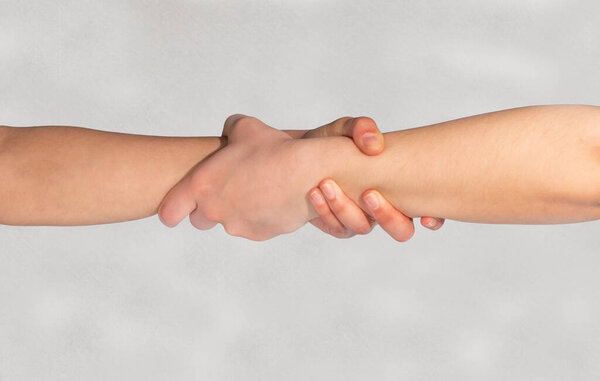 Handshake, helping hand. Two hands concept. Hands holding each other on the outstretched arm. Close up isolated arm, hand. Gestures of help, rescue or handshake between people, friends, partners or colleagues.