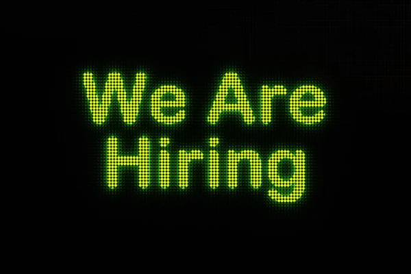 We are hiring, displayed on a screen. Dark LED screen with the words \