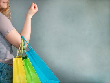 Kıvırcık saçlı kadın renkli alışveriş torbaları taşıyor. Portre alışverişi, renkli çantalı kadın.
