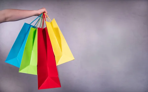 Hand holds colored shopping bags. Portrait shopping, woman with colored bags