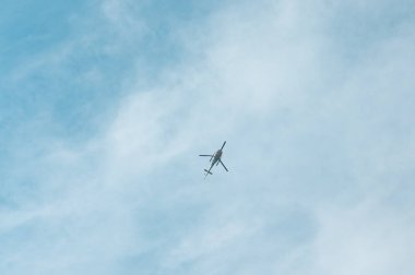 Aşağıdan bir helikopter. Pervaneli, aşağıdan uçan helikopter. Bulutlu mavi gökyüzü. 
