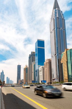 Dubai, Birleşik Arap Emirlikleri - 20 Nisan 2023: Gökdelenlerle Şeyh Zayed Yolu 'na bakın. Ön planda mavi arabalar var. Arka planda bulutlar olan mavi gökyüzü. 