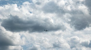 Bulutlar arasındaki ticari uçak. Yoldan geçen uçak kümülüs bulutları tarafından çerçevelenmiş gökyüzünde uçar.. 