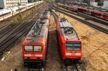 İki elektrikli lokomotif. Frankfurt Almanya - 19 Temmuz 2023: Yanlarda tren lokomotifleri. Sinyal sistemleri, demiryolu bağlantıları ve şalterleri. ICE treni sol tarafta..